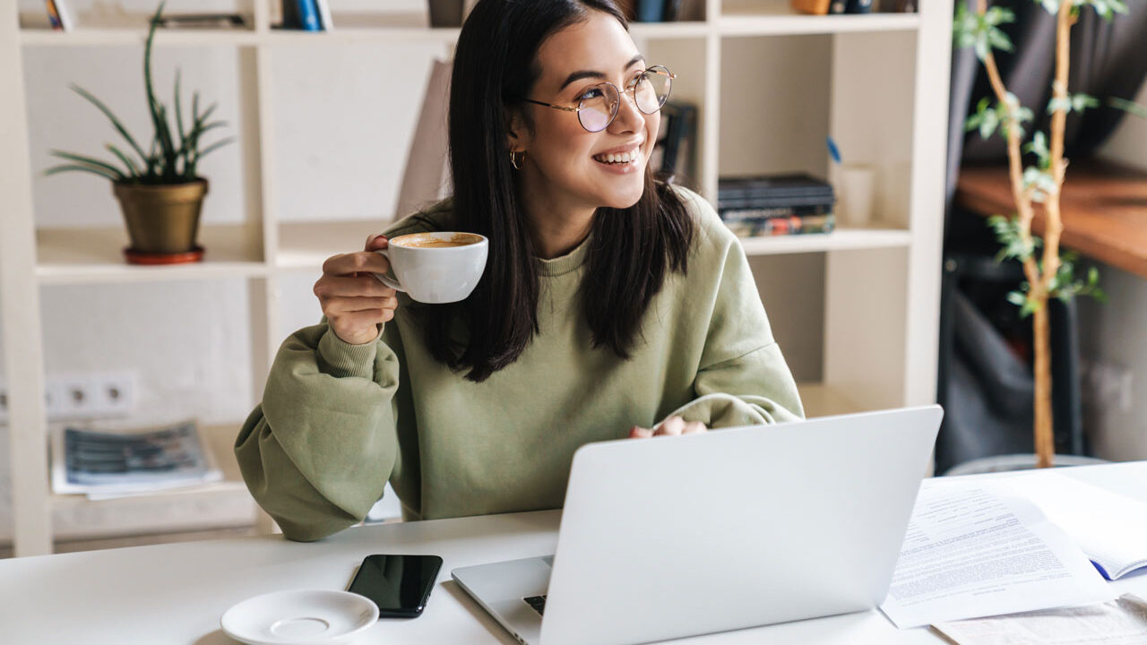 Studentin mit Laptop und Kaffeetasse beim Lernen