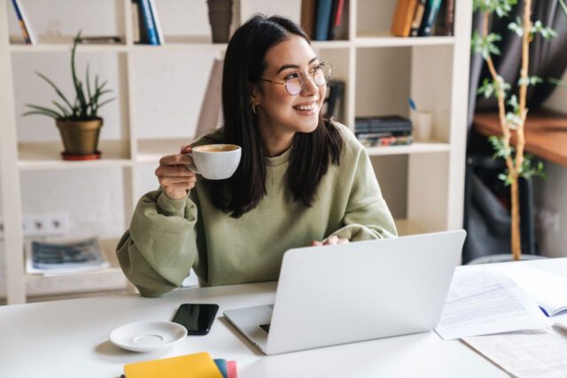 Studentin mit Laptop und Kaffeetasse beim Lernen