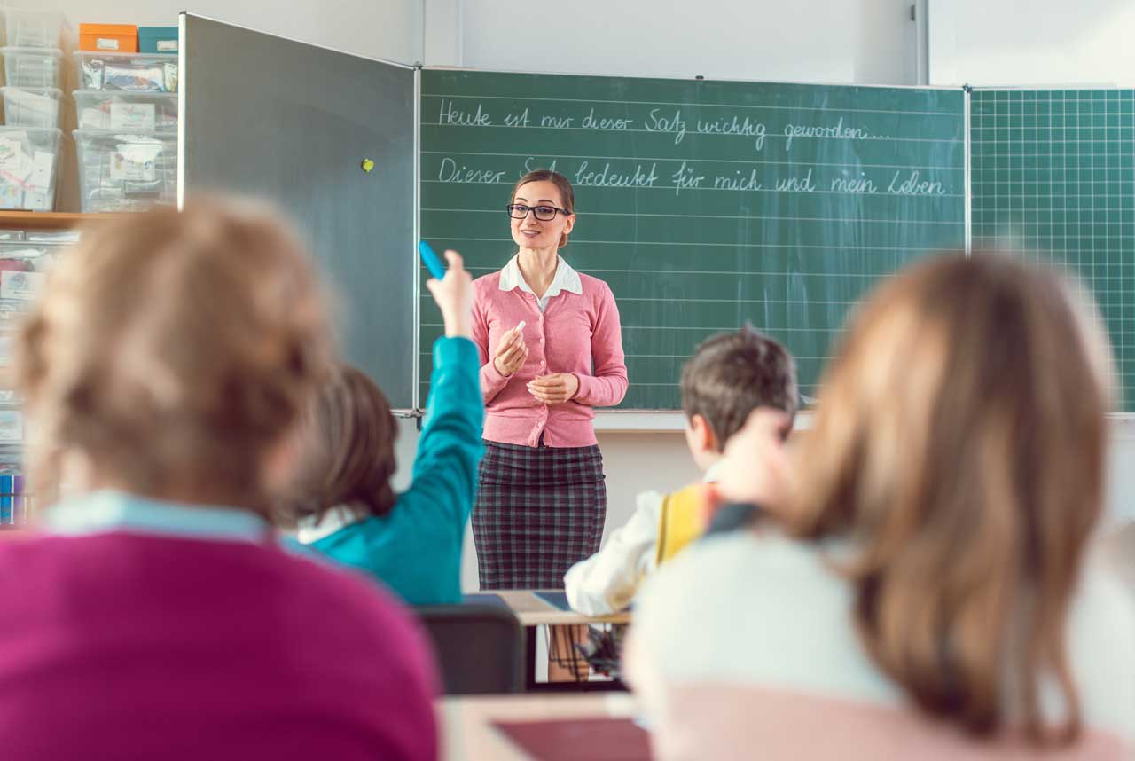 Lehrerin schreibt an Tafel in moderner Schule