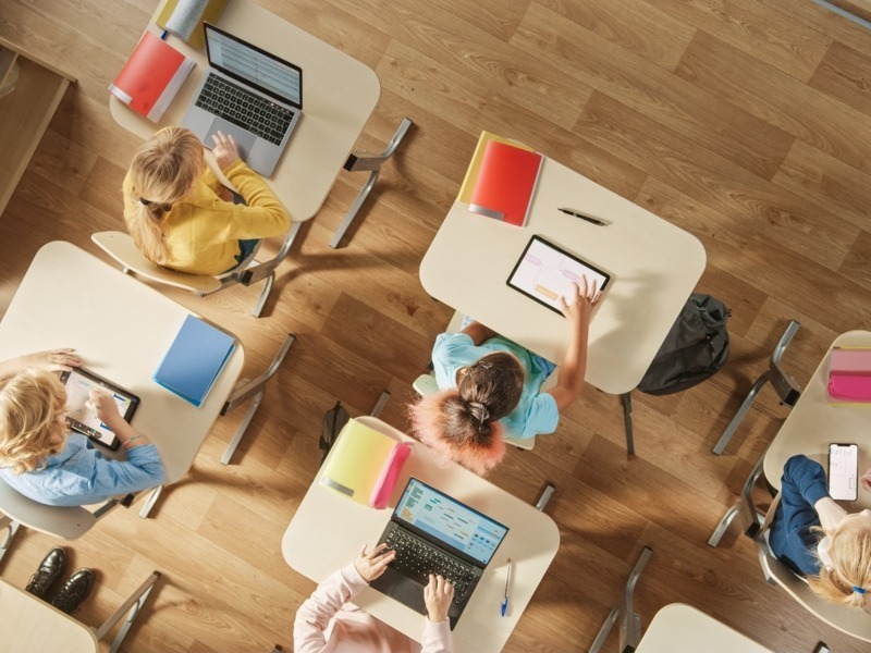 Kinder sitzen an ihrer Schulbank mit PCs und digitalen Tablets für Aufgaben; Gorodenkoff - adobe stock