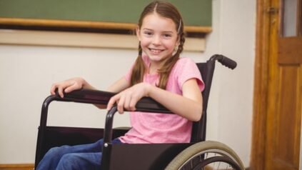 Behinderte Schülerin im Rollstuhl lächelt